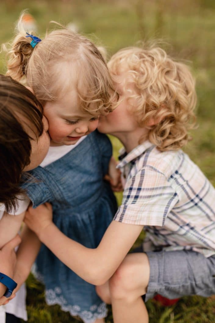 two brothers are kissing their younger sister in her cheeks. family photo shoot in Basingstoke, Hampshire. Basingstoke photographer. Ewa Jones Photography