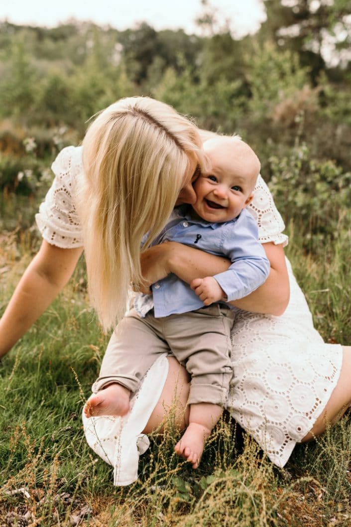 Mum is cuddling little boy and kissing him on his cheek. Natural lifestyle photography in Hampshire. Ewa Jones Photography