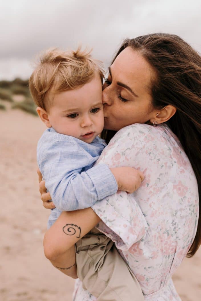 Mum is kissing her little boy in his cheek. Beach family photo shoot in Hampshire. Ewa Jones Photography