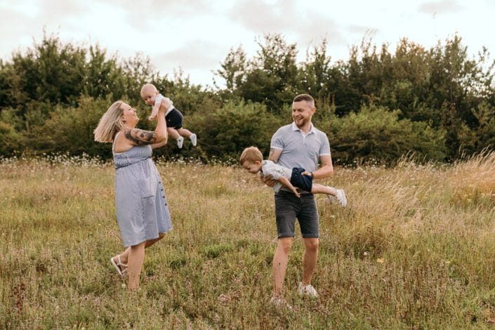 family of four are dancing in the field of flowers. Natural lifestyle photography in Basingstoke, Hampshire. Ewa Jones Photography