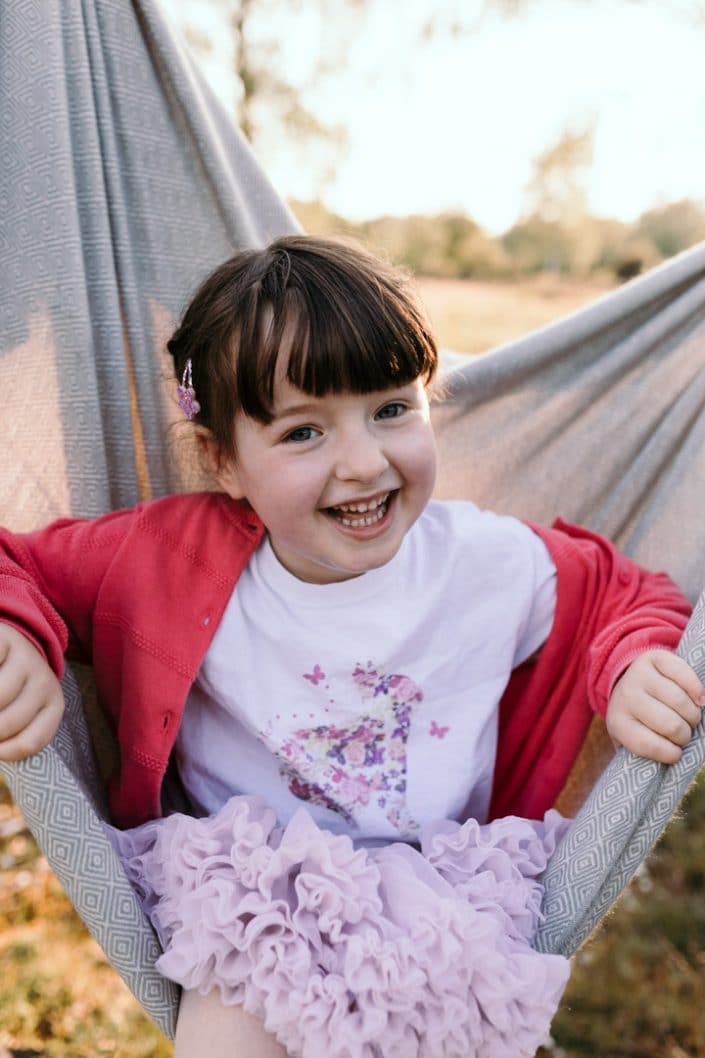 Little girl is sitting in the blanket and smiling to the camera. Hampshire family photographer. Ewa Jones Photography