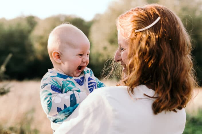 Mum is looking at her baby boy and laughing to him. Boy is laughing back at his mum. Lovely candid photograph of mum and son love. Family photographer in Hamsphire. Ewa Jones Photography