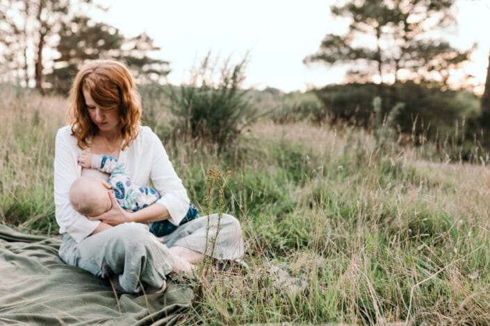 Mum is sitting on the blanket and breastfeeding her little boy. Lovely sunset photography in Hampshire. Family photography in Hampshire. Ewa Jones Photography