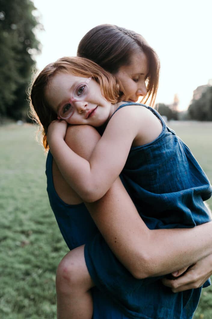 Girl is resting on mum's shoulders and cuddling to her. Candid photography. Natural family photoshoot in Hampshire. Ewa Jones Photography