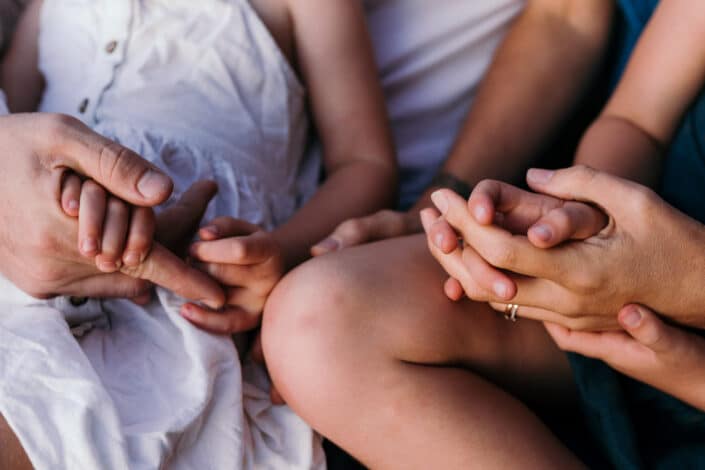 Hands connection, family sitting on the grass telling stories. Family holding each other, close up details. Family photoshoot in Hampshire, Ewa Jones Photography