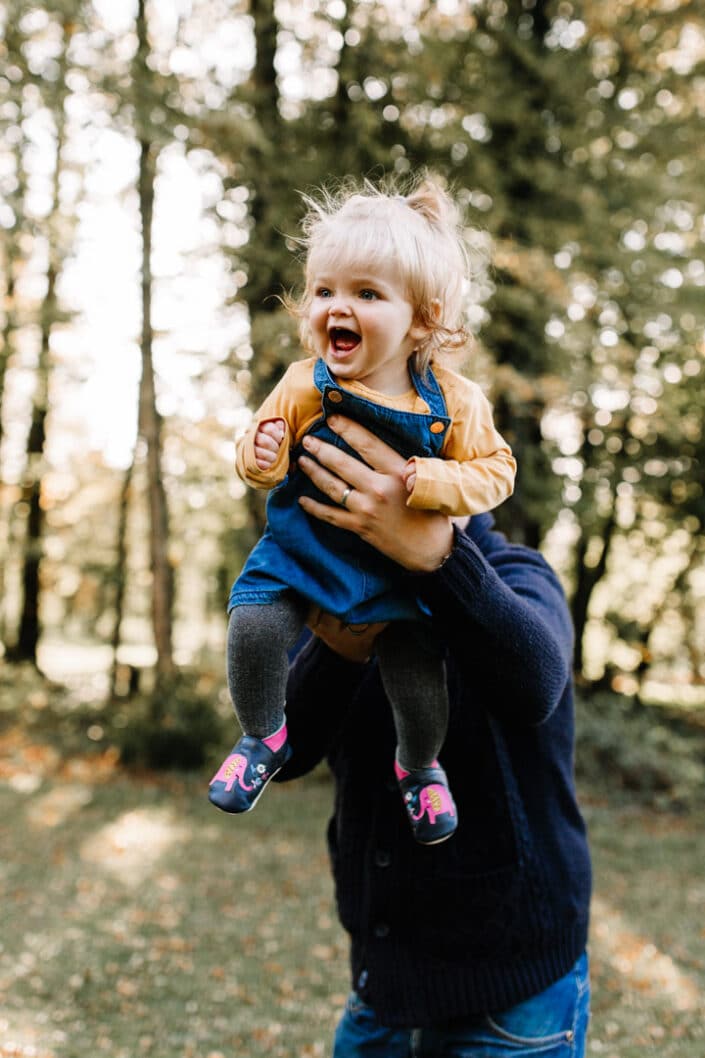 Dad is swinging his little girl high in the air. Autumn family photo shoot in Hampshire. Family photography in Hampshire. Ewa Jones Photography