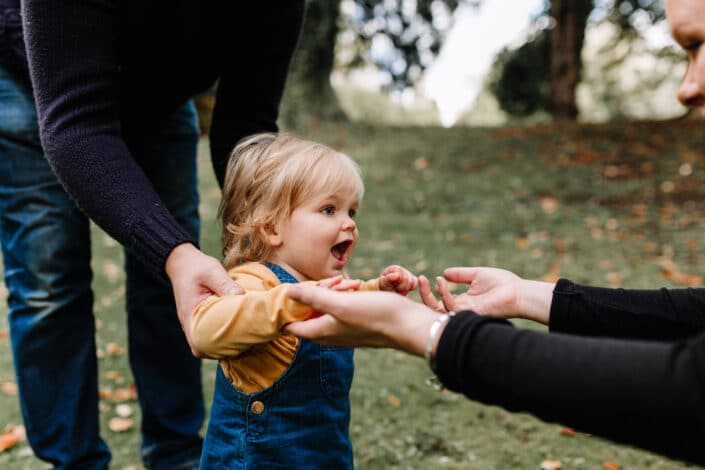 Little girl is trying to walk and holding her hands and walking towards mummy. Lovely family autumn photo session in Hampshire. Family photographer in Hampshire. Ewa Jones Photography