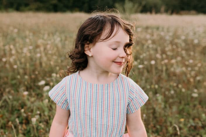 Little girl has her eyes closed and her little hair has flicked onto her eye. Lovely candid and emotional photograph. Family photographer in Hampshire. Ewa Jones Photography