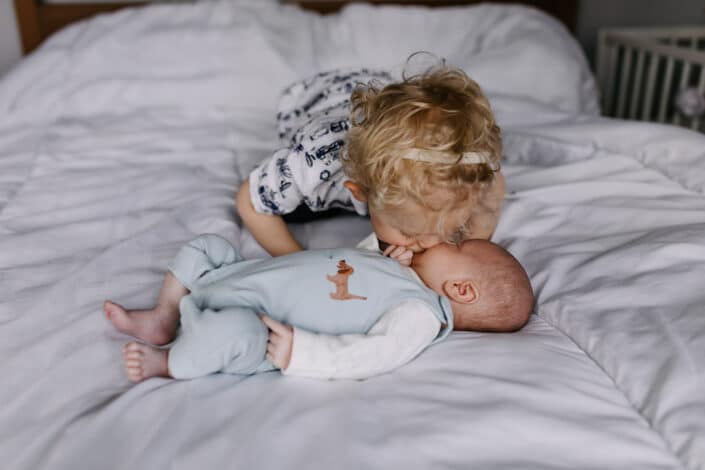 Older brother is kissing his little baby brother. Lifestyle newborn baby photography. Newborn baby photography in Reading, Berkshire. Ewa Jones Photography