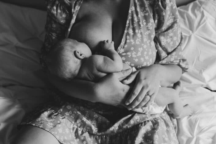 Mum is breastfeeding her newborn baby boy. Black and white newborn photography in Hampshire. Ewa Jones Photography
