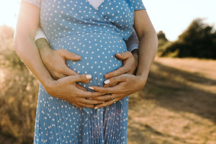 Expecting parents are standing and holding bump. Sunset maternity photography in Hampshire. Ewa Jones Photography