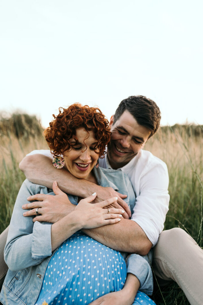 Husband and wife are holding hands together and laughing. Maternity lifestyle photo session in Hampshire. Ewa Jones Photography