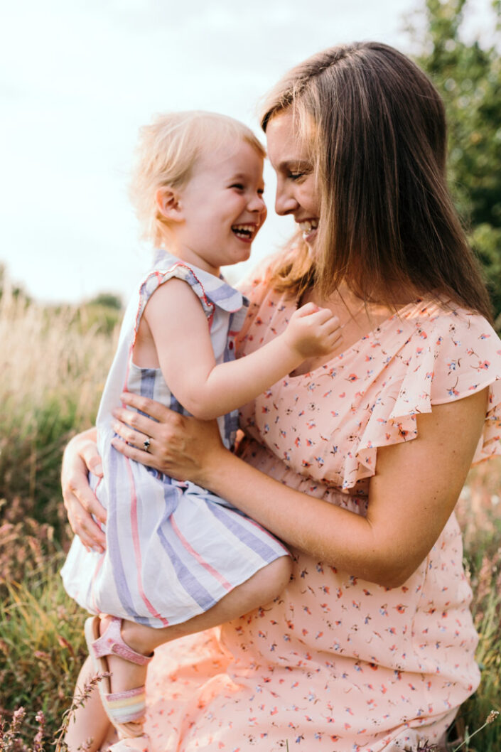 Pregnant mum and her daughter are laughing. Lovely sunset maternity and family photo session in Hampshire. Ewa Jones Photography