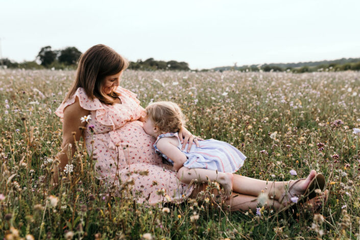 Little girl is kissing mummy bump. Lovely mum and daughter moment. Family and maternity lifestyle photography in Basingstoke. Ewa Jones Photography