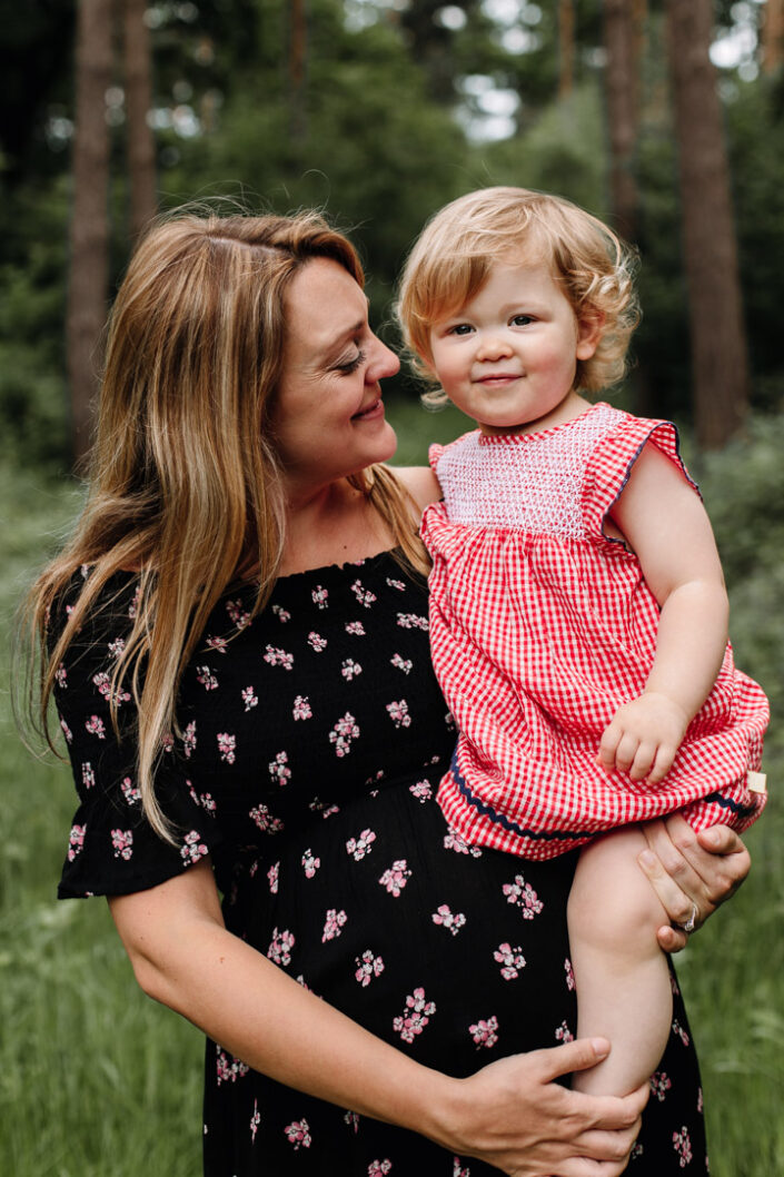 Mum is holding her toddler girl and looking at her. Lovely maternity photo shoot in Basingstoke. Ewa Jones Photography