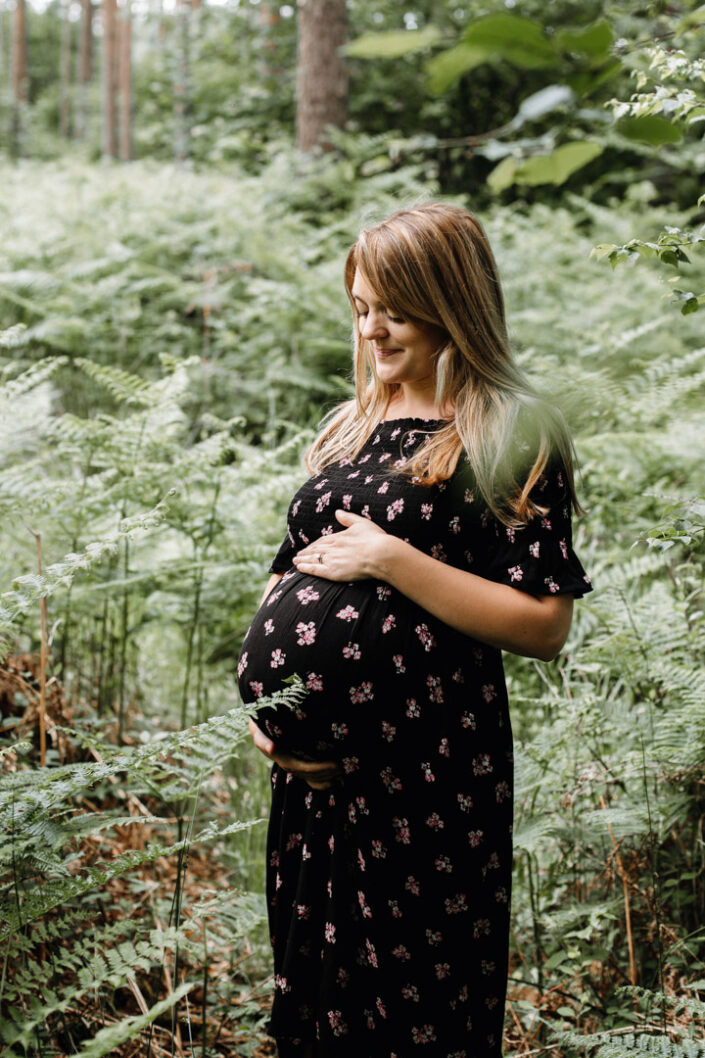 Mum is standing in the lovely fern an looking down on her bump. Maternity photography in Hampshire. Ewa Jones Photography