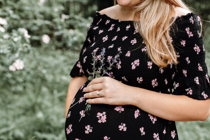 Expecting mum is holding flowers in her hand. Close up shoot of pregnant mum. Expecting mum photography session in Basingstoke. Ewa Jones Photography