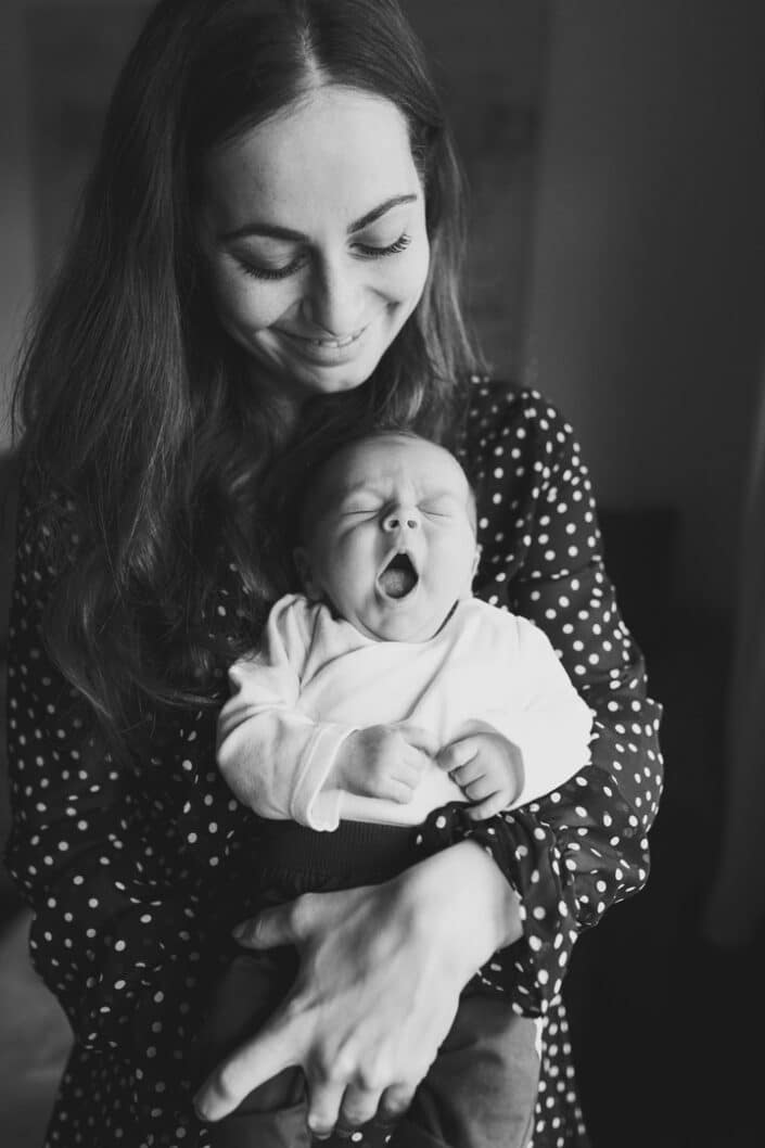 Mum holding a newborn baby. Newborn baby is yawning. Black and white newborn photoshoot. Ewa Jones Photography