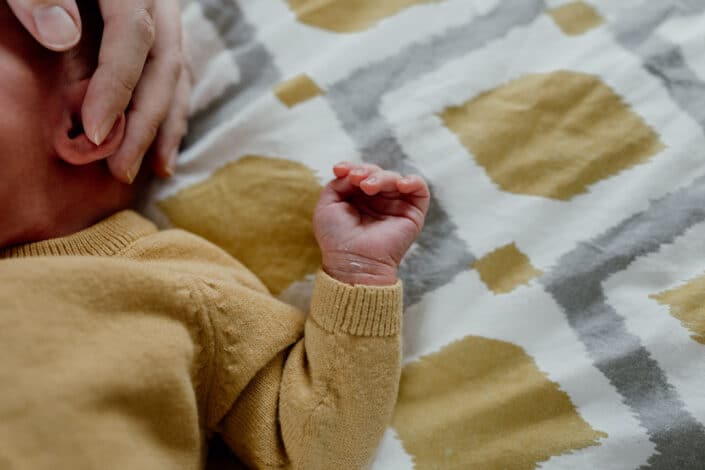 Detail shoot of newborn baby hand. Baby is laying on bed and in shoot you can only see baby's hand. Newborn baby photographer in Basingstoke, Hampshire. Ewa Jones Photography