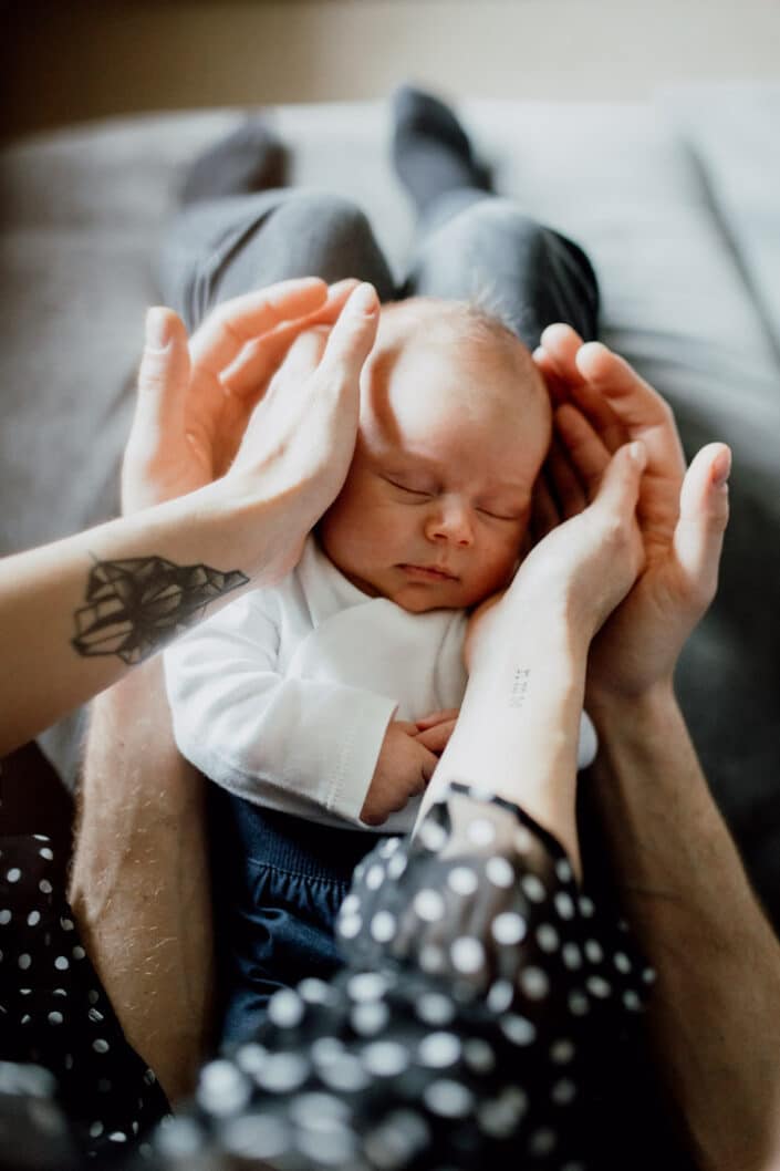 Mum and dad are holding newborn baby head. Close up details during newborn photoshoot in Hampshire. Ewa Jones Photography