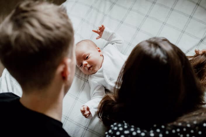 Mum and dad looking at the newborn baby on the bed. Newborn baby photography in Basingstoke, Hampshire. Ewa Jones Photography