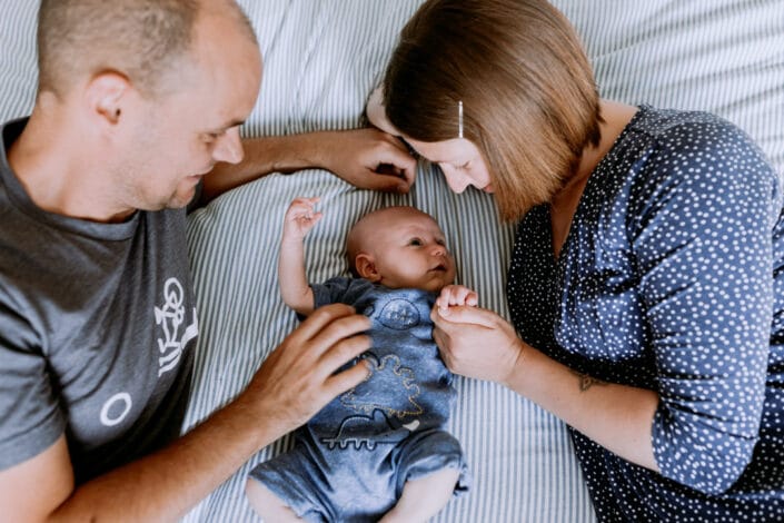 In home lifestyle newborn photo session. Mum and dad and baby on bed. Hampshire newborn photography. Ewa Jones Photography