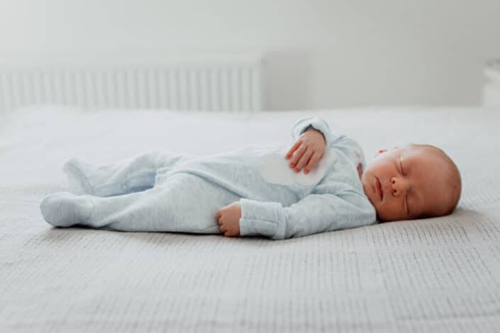 Newborn baby laying on the bed and sleeping. Shoot on the bed. Newborn baby photoshoot in Basingstoke, Hampshire. Ewa Jones Photography