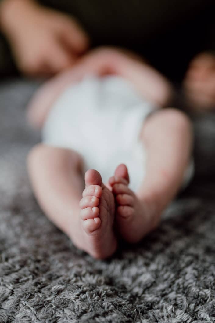 Newborn baby laying on the bed. Close up of a newborn baby feet. Natural newborn baby photoshoot in Basingstoke. Hampshire. Ewa Jones Photography