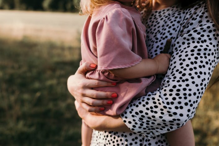 Mum holding a girl in the field. Detail shoot during family photoshoot in Basingstoke. Hampshire. Ewa Jones Photography