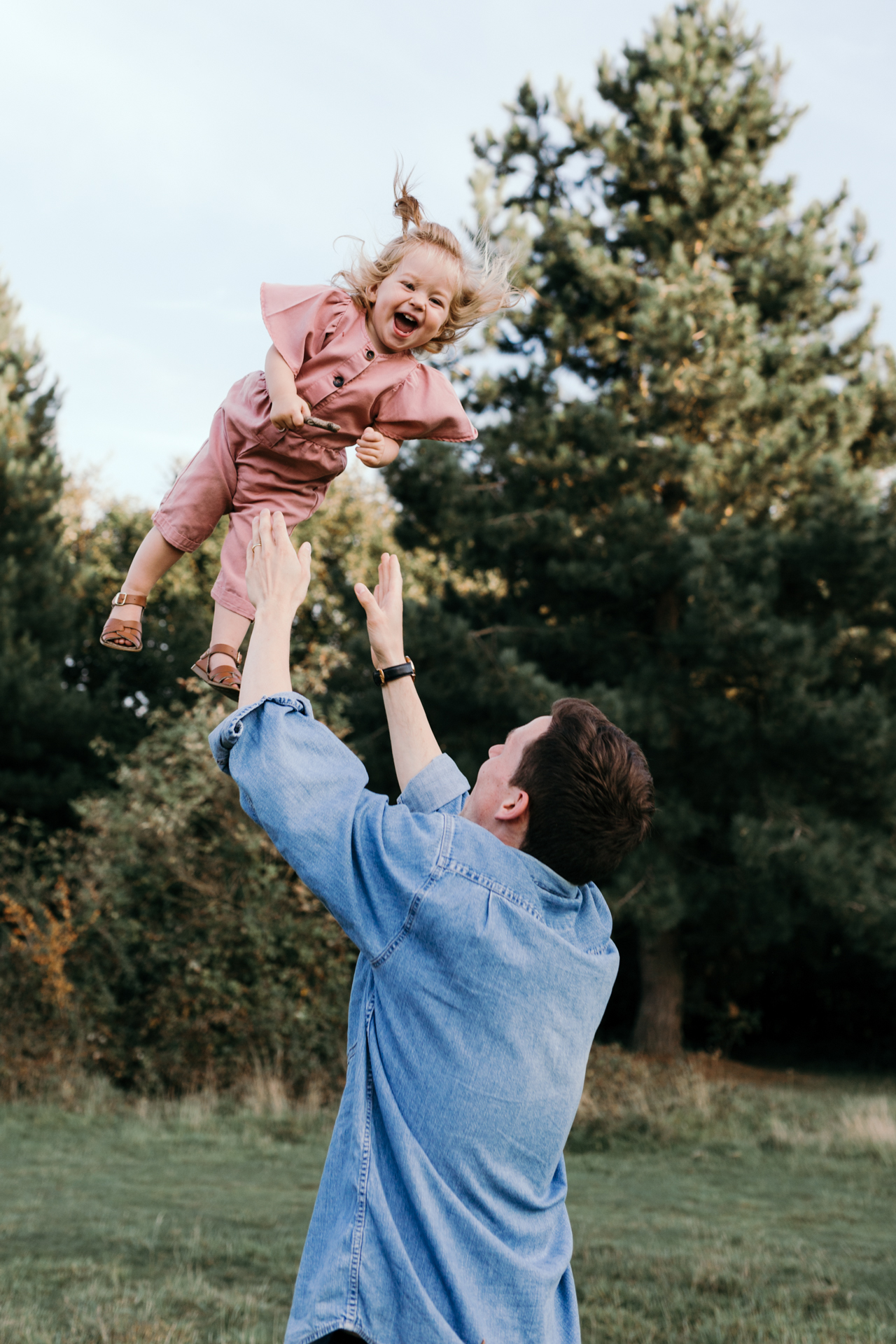 Dad throwing girl into the air. Girl is laughing. Family photoshoot in Basingstoke. Ewa Jones Photography