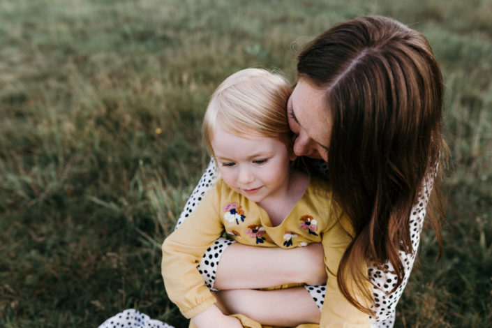 Happy girl held by her mum. Girl is wearing a yellow dress. Family photoshoot in Basingstoke. Ewa Jones Photography