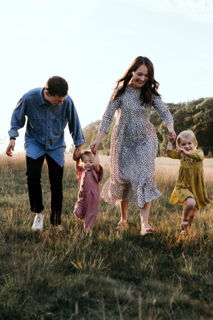 Family running on the field during sunstet family photoshoot in Basingstoke. Hampshire. Ewa Jones Photography