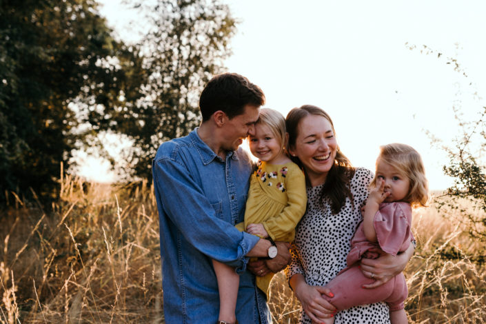 Mum and dad holding daughters. Back lit photography. Family photoshoot in Basingstoke. Ewa Jones Photography