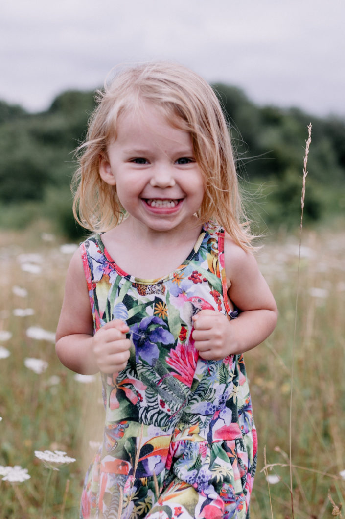 Girl smiling in wild flowers by Ewa Jones Photography