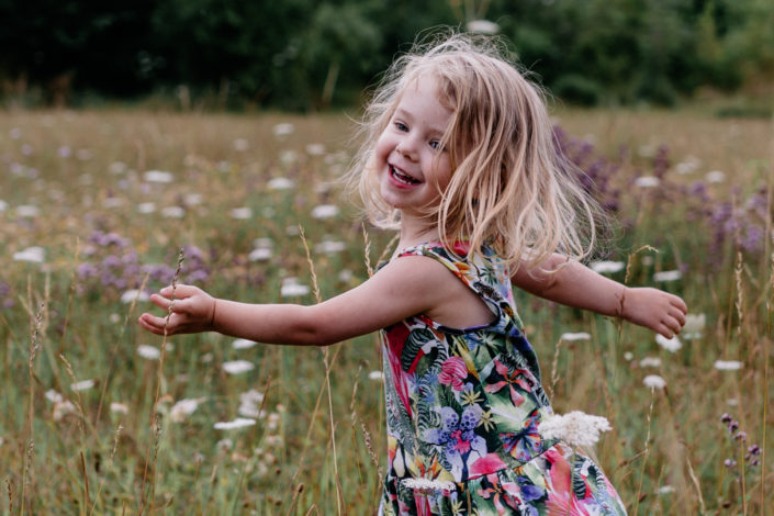 Little girl dancing in wild flowers by Ewa Jones Photography