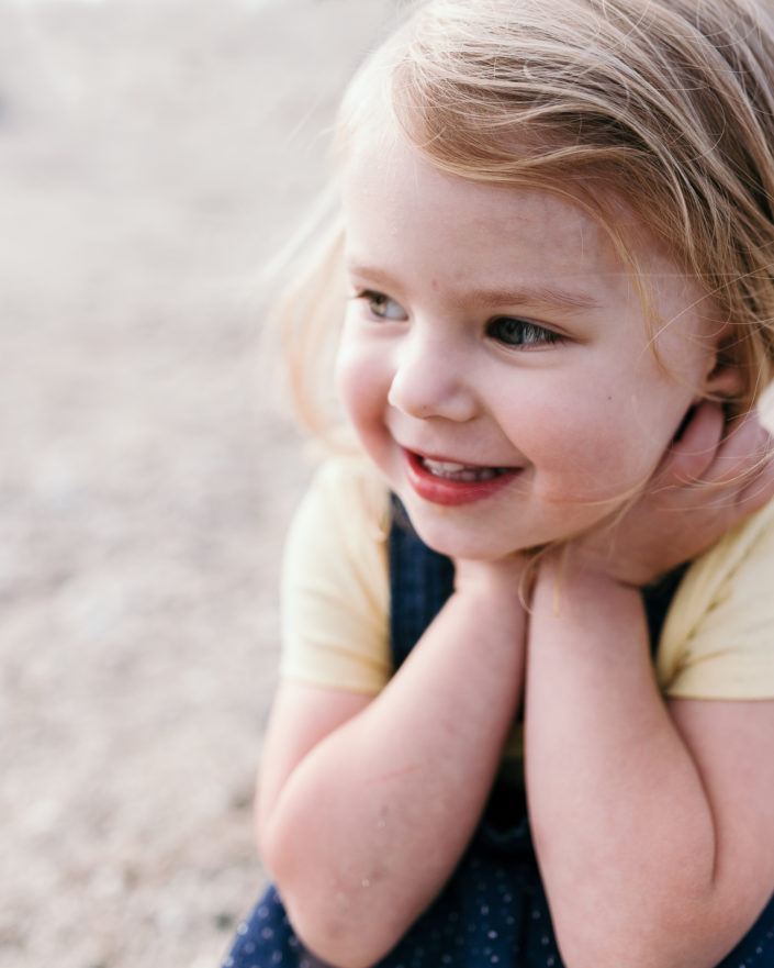 Happy girl watching the waves on the beach by Ewa Jones Photography