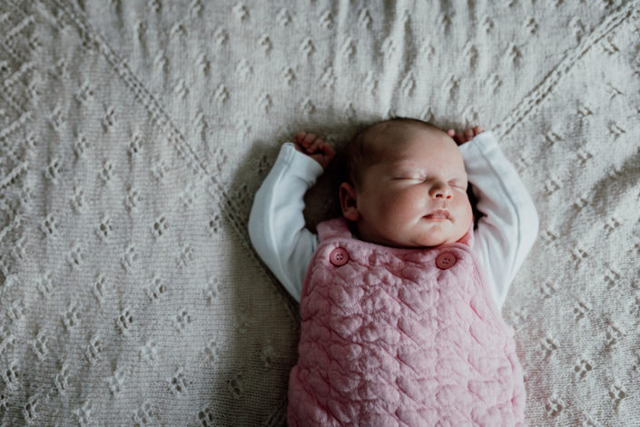 Newborn baby sleeping on the bed with hands up. My six-must have poses for a newborn photoshoot.Baby sleeping on a lovely blanket. Newborn photography in Hampshire. Ewa Jones Photography