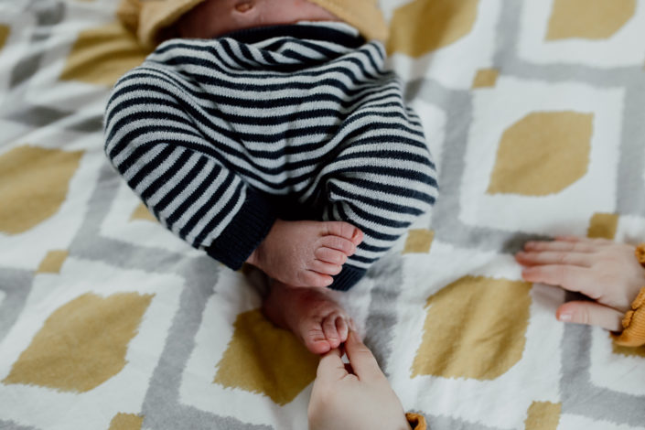 Newborn feet details. Older sibling is touching newborn baby brother feet. Newborn photoshoot in Hampshire. Ewa Jones Photography