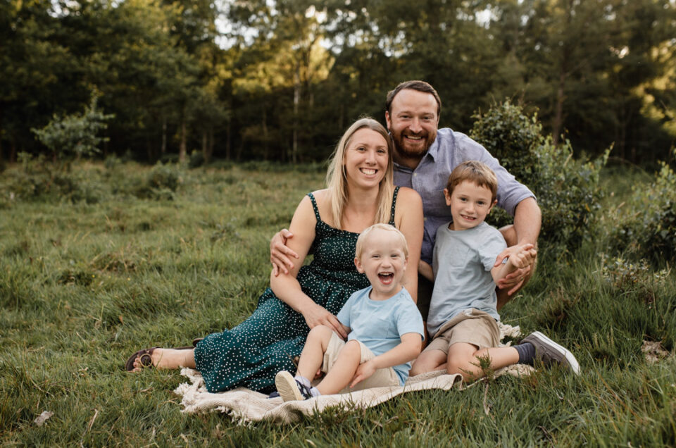 Family is sitting on the blanket and laughing. Family photo session with Emma Reed. Family lifestyle photography in Hampshire. Ewa Jones Photography