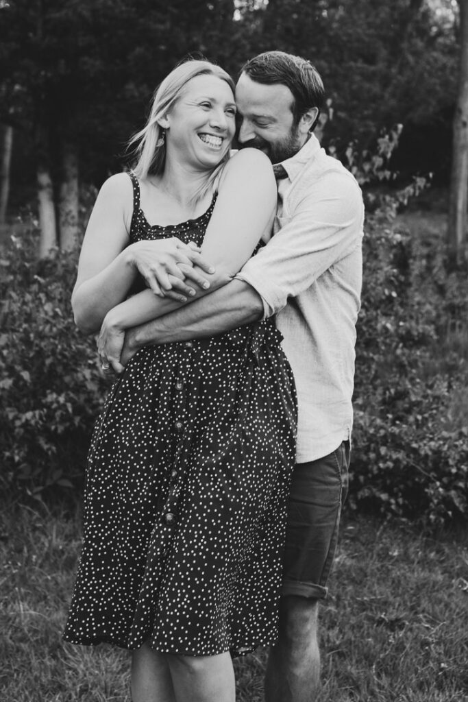Wife and husband are hugging. Husband is kissing his wife shoulder. Couple photography. Ewa Jones Photography