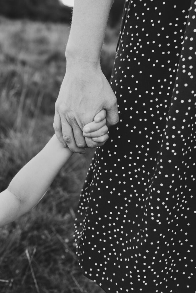 Mum is holding her son's hand. Black and white candid photography. Family photography in Hampshire. Ewa Jones Photography