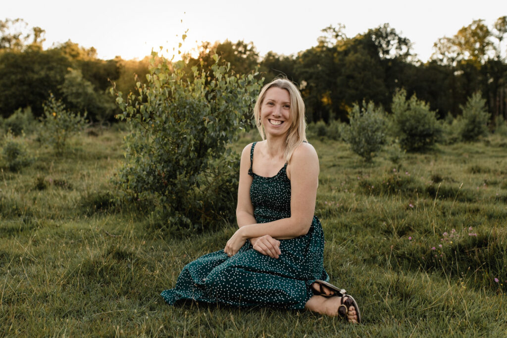 Mum is sitting on the grass and looking at the camera. She is smiling. Family lifestyle photography. Family photo session with Emma Reed. Ewa Jones Photography