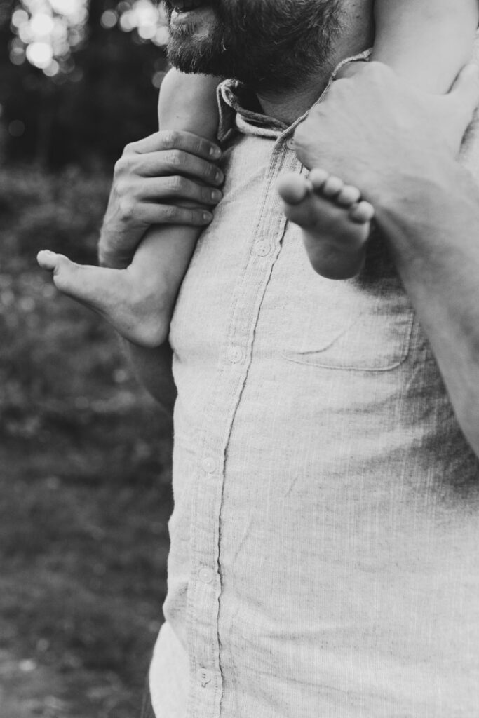 Dad is holding his son on his shoulders. Black and white photography. Family photographer in Basingstoke. Ewa Jones Photography