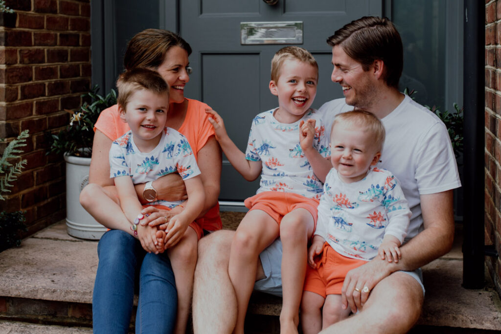 Mum dad and three boys are sitting on the step in front of their house. What to wear for a family photo session. family doorstep photo sessions. Ewa Jones Photography