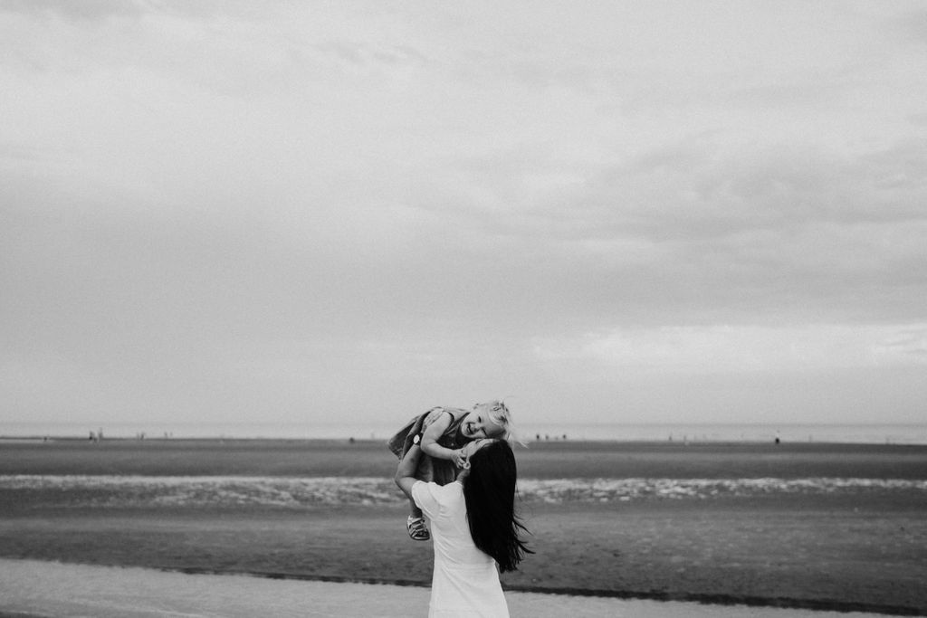 Mum is lifting her little girl in the air. Family photo shoot during sunset