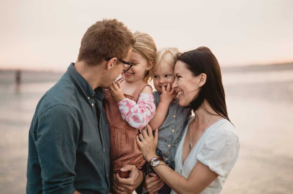 family photo session at the beach. Family is cuddling to each other.