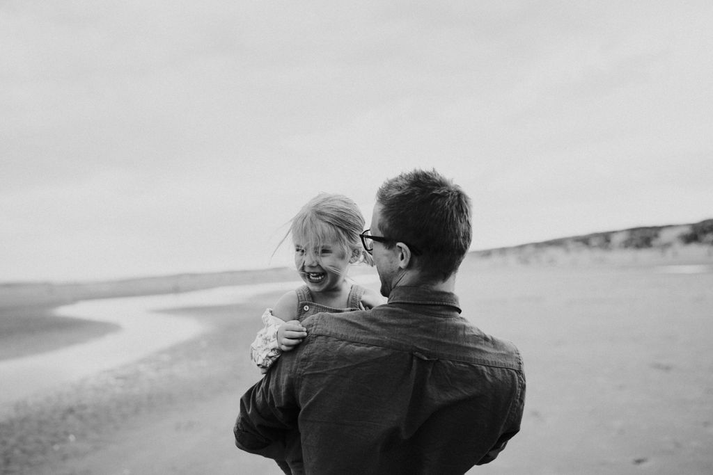 Little girl is laughing and dad is looking at her. Family photo session
