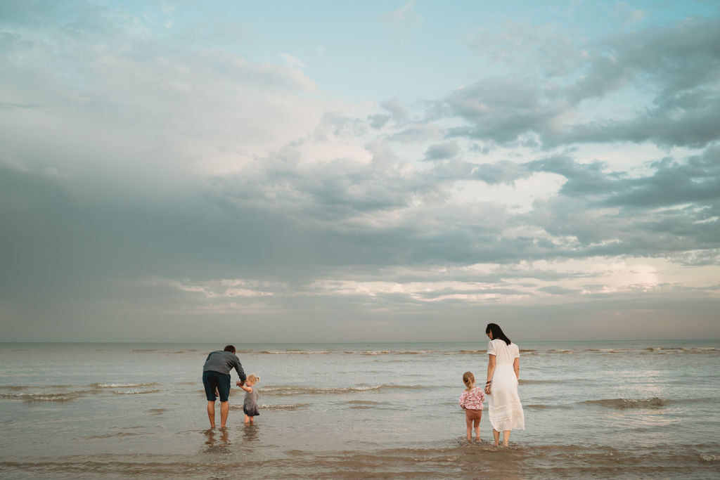 family of four are standing in the sea. Our first family photo session