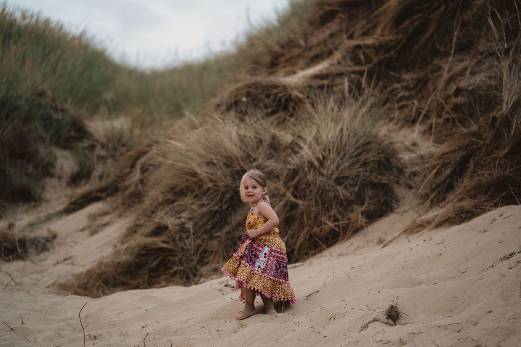 Little girl is running down on the sand dunes. Lifestyle family photography