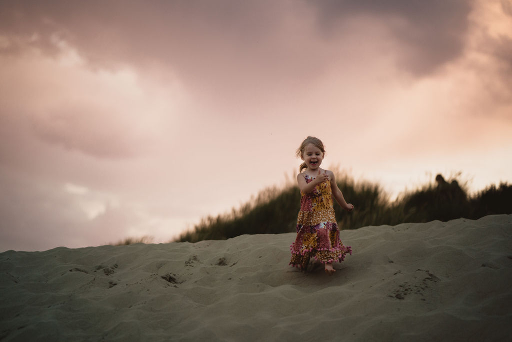Little girl is running down on the sand dunes. Lifestyle family photography